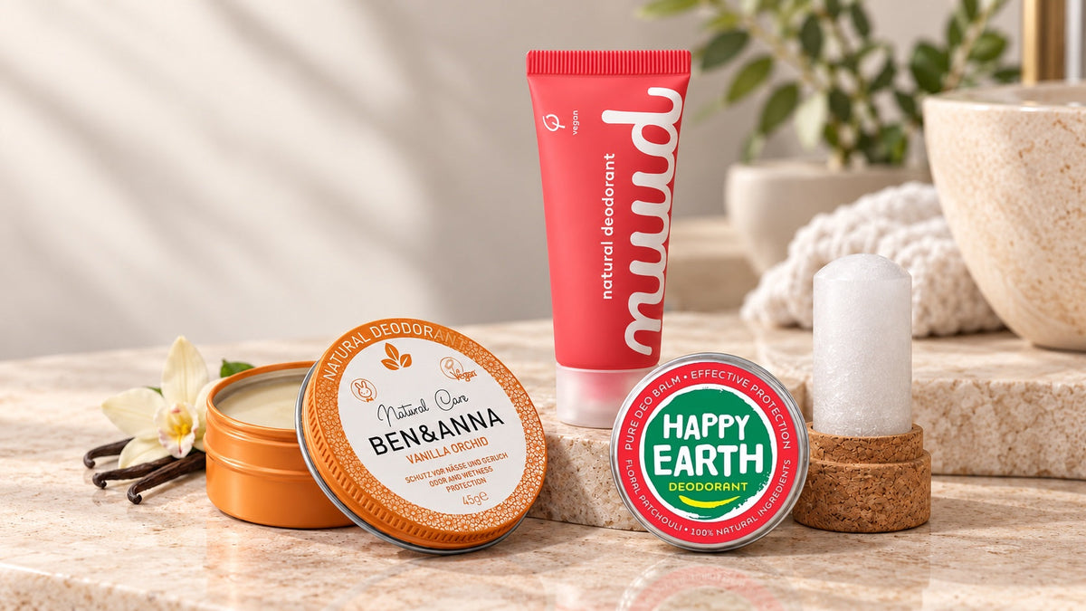Nuud deodorant, een open blikje Ben & Anna, Happy Earth deodorantbalsem en een kristalstick op een lichte badkamerplank.