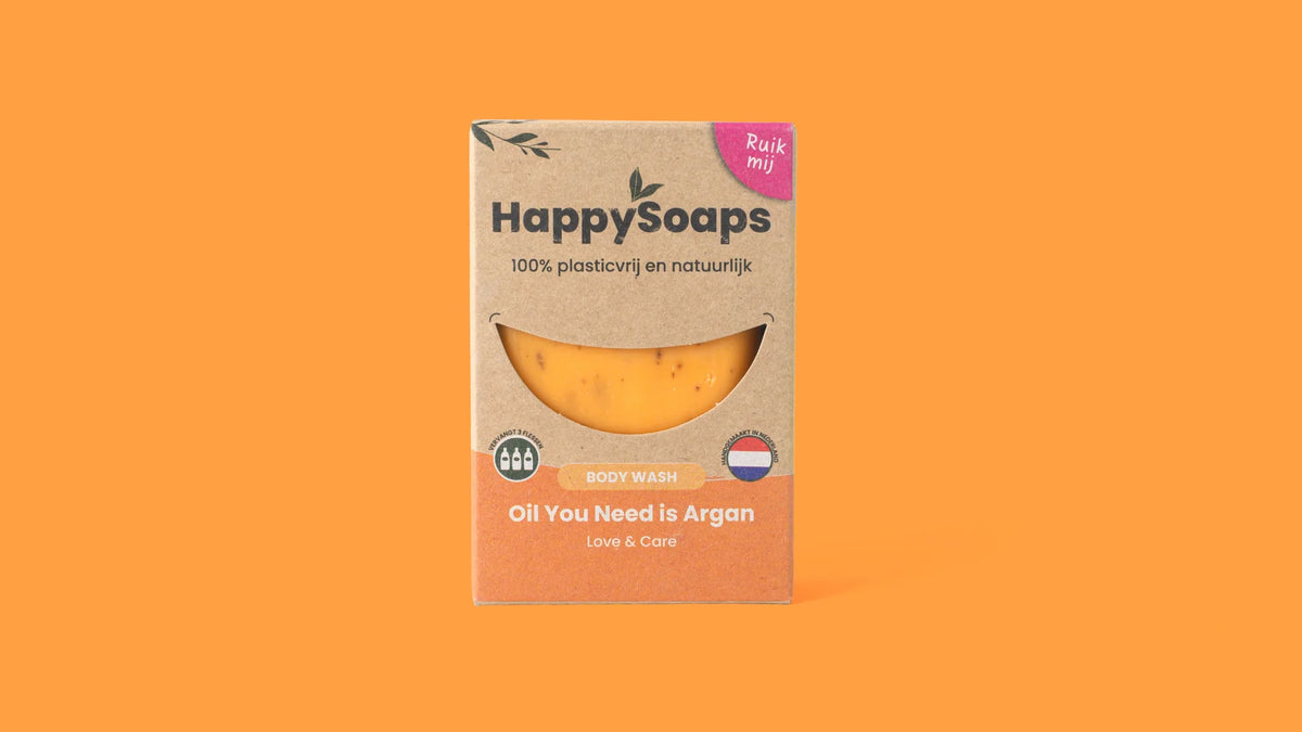 Verpakking van HappySoaps Oil You Need is Argan Body Wash Bar op een oranje achtergrond