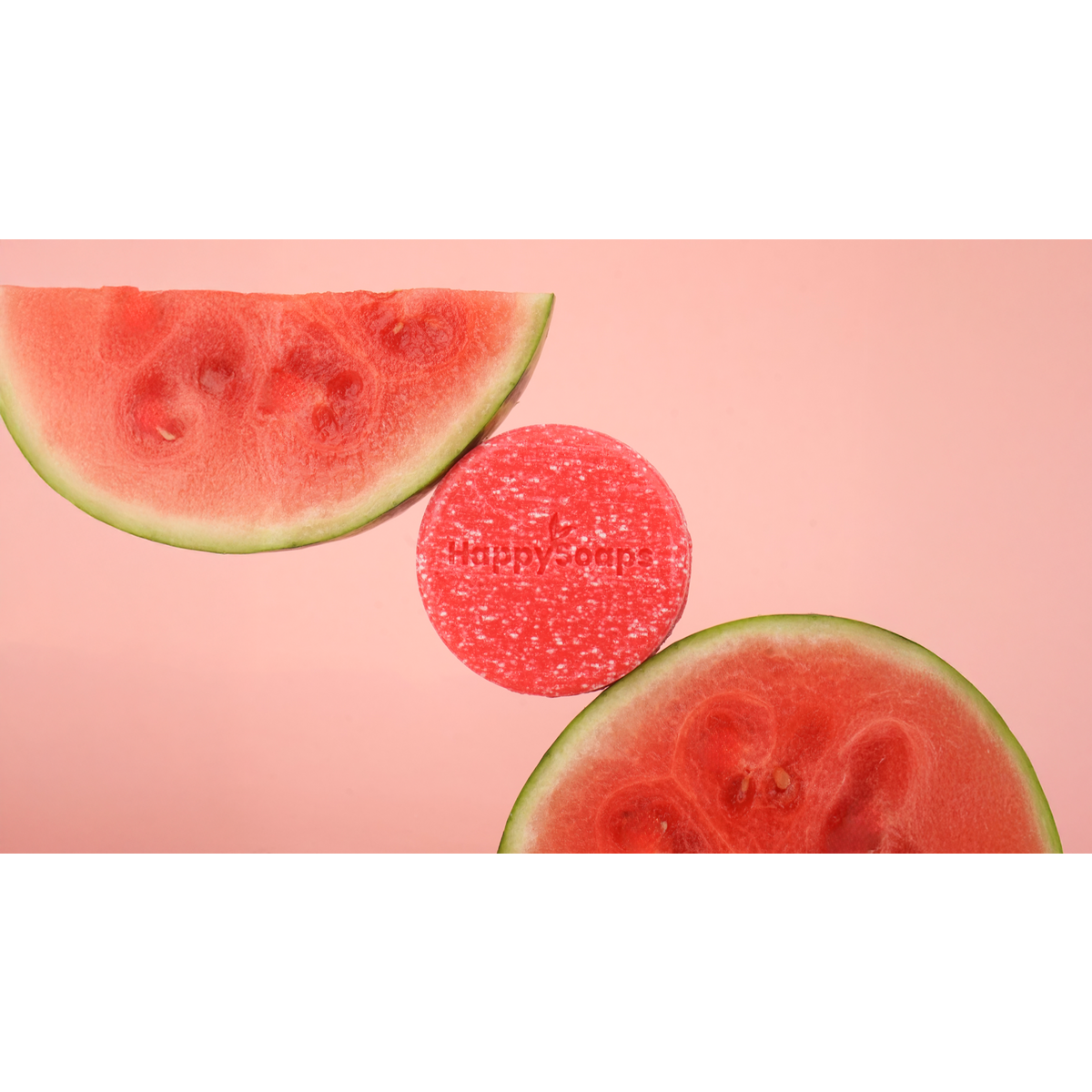 HappySoaps You’re One in a Melon shampoo bar tussen twee stukken watermeloen op een roze achtergrond