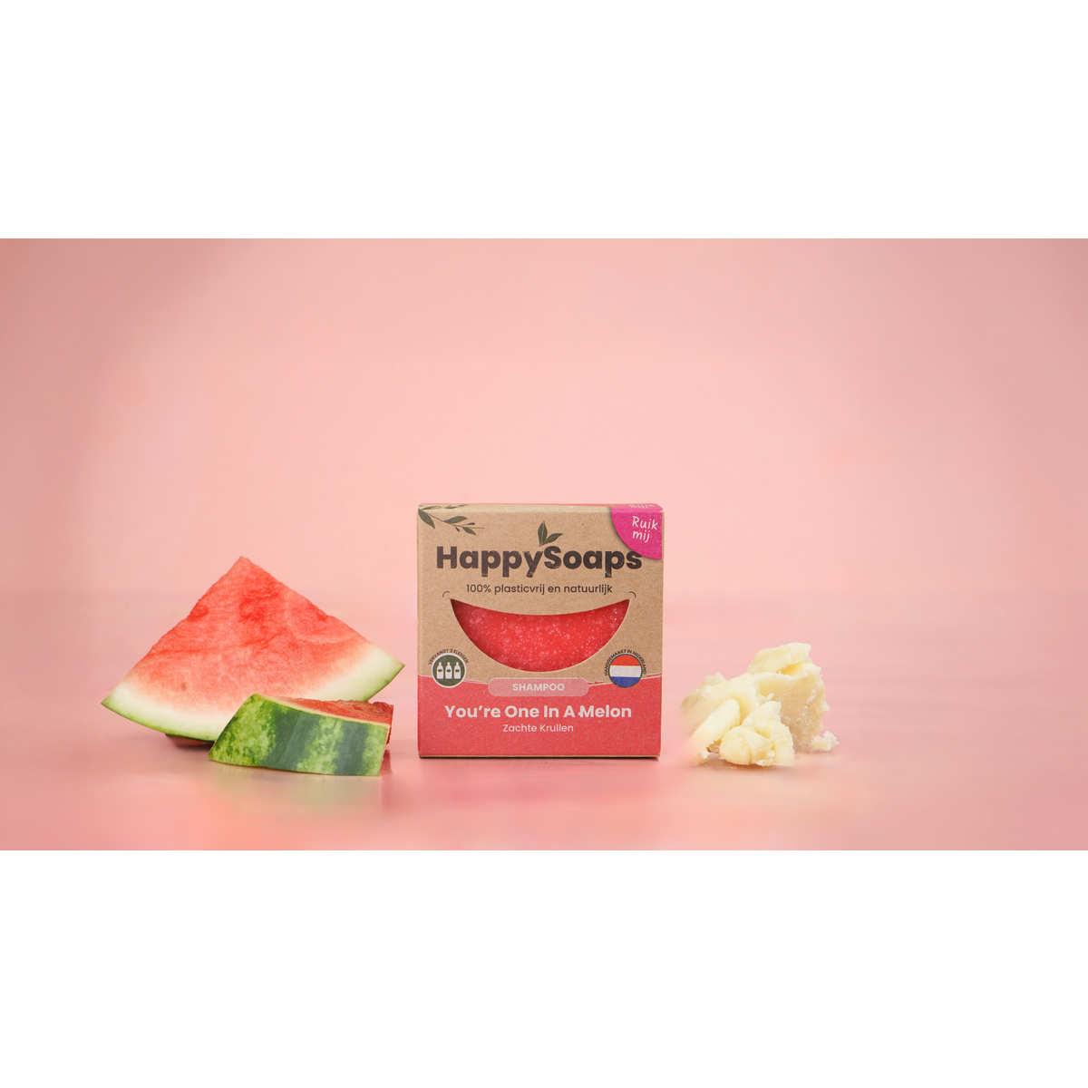 HappySoaps You’re One in a Melon verpakking naast stukken watermeloen op een roze achtergrond